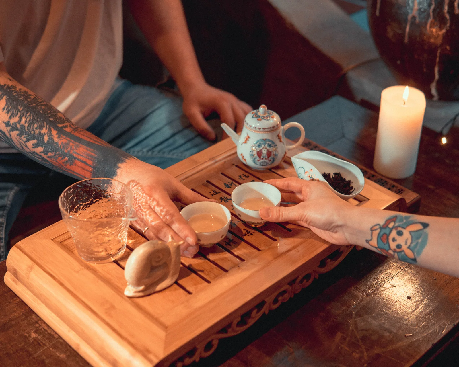 People sharing tea around a small wooden tea table